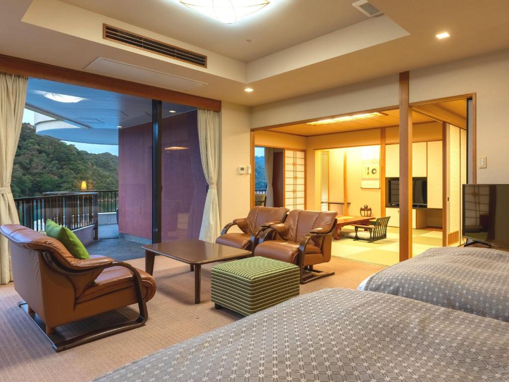 une chambre avec un lit et un salon dans l'établissement Kumano-bettei Nakanoshima, à Katsuura