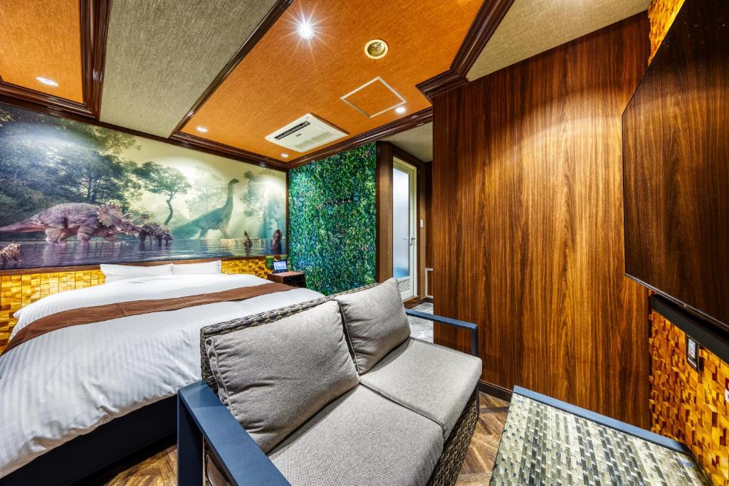 une chambre avec un lit et un canapé dans l'établissement Hotel Artia Dinosaur hirakata -Adult Only, à Hirakata