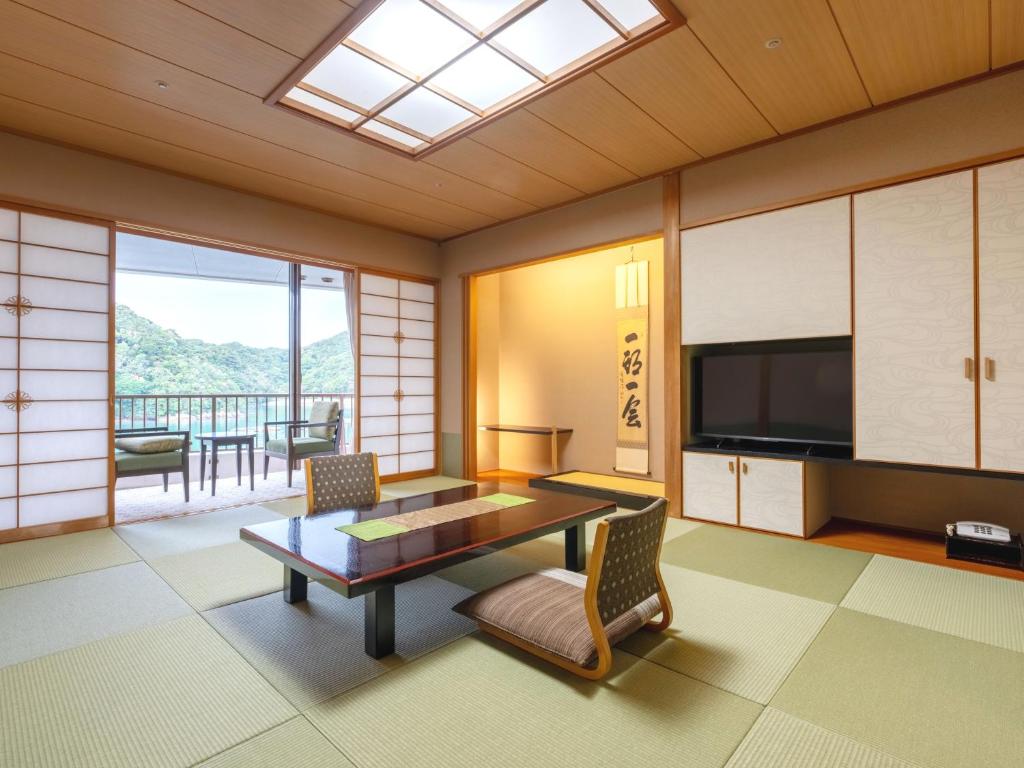 un salon avec une table et une télévision dans l'établissement Kumano-bettei Nakanoshima, à Katsuura
