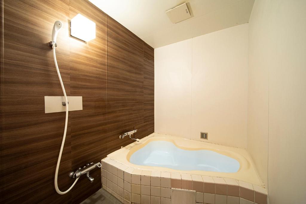 une baignoire dans une salle de bain avec douche dans l'établissement リベラル 神戸三宮男塾ホテルグループ, à Kobe