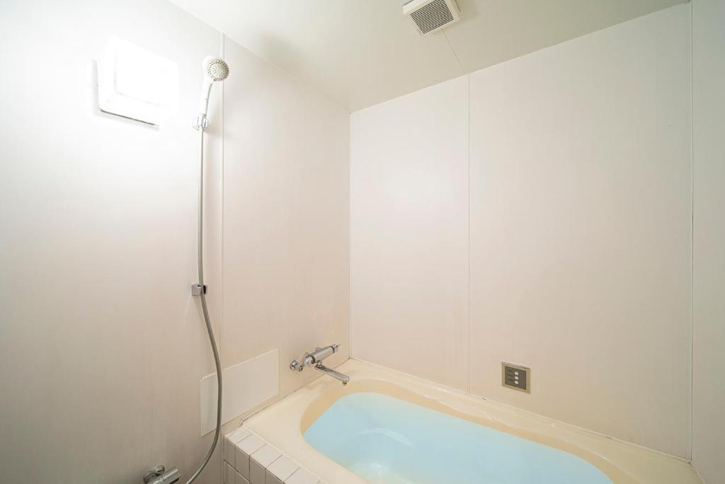 une baignoire dans une salle de bain avec douche dans l'établissement リベラル 神戸三宮男塾ホテルグループ, à Kobe