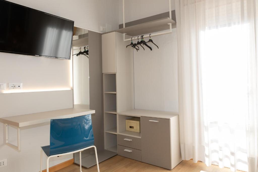 une pièce avec une télévision et une chaise bleue dans l'établissement Hotel Arizona, à Lido di Jesolo