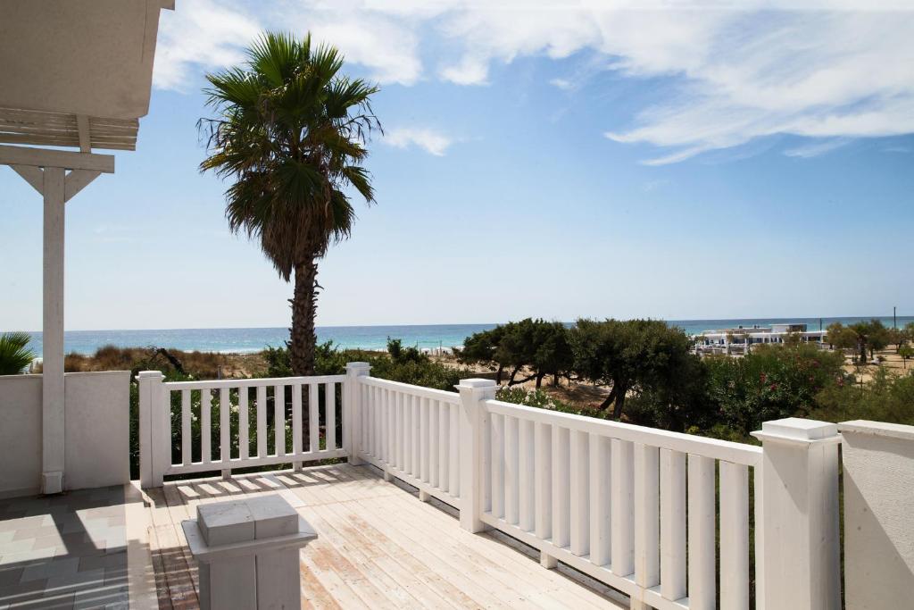 d'un balcon avec une clôture blanche et un palmier. dans l'établissement Lido degli Angeli Case Vacanza-Beach, à Punta Prosciutto