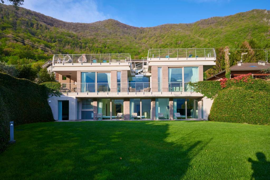 une grande maison avec une pelouse devant dans l'établissement Villa Costanza- private heated pool, steam room & sauna - Bellagio Village Residence, à Oliveto Lario