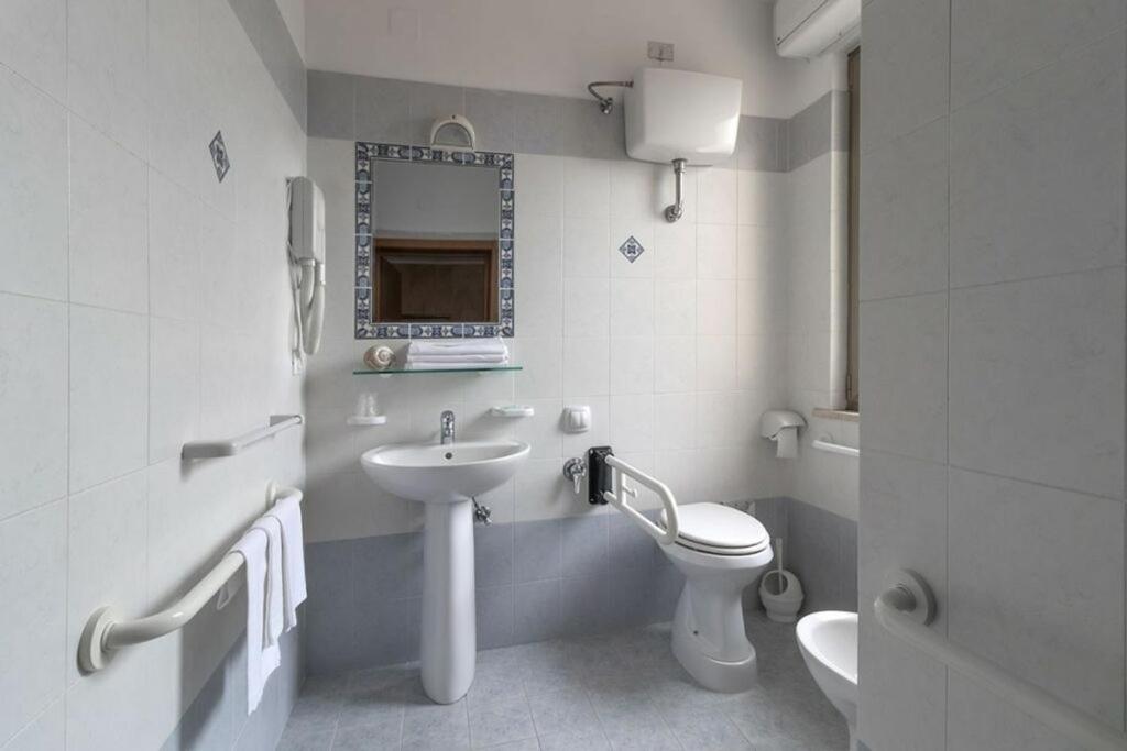 une salle de bain blanche avec un lavabo et des toilettes dans l'établissement Hotel Corallo, à Giulianova 9 autres photos