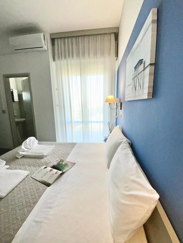 - une chambre avec un grand lit blanc et un mur bleu dans l'établissement Hotel Alfa - SPIAGGIA INCLUSA con Formula All Inclusive, à Rimini