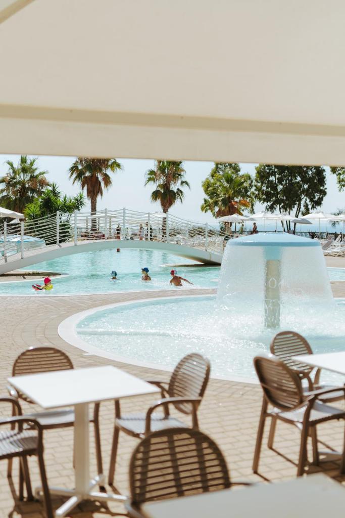 - une piscine avec des tables, des chaises et des personnes dans l'eau dans l'établissement Grotta del Saraceno, à Vasto