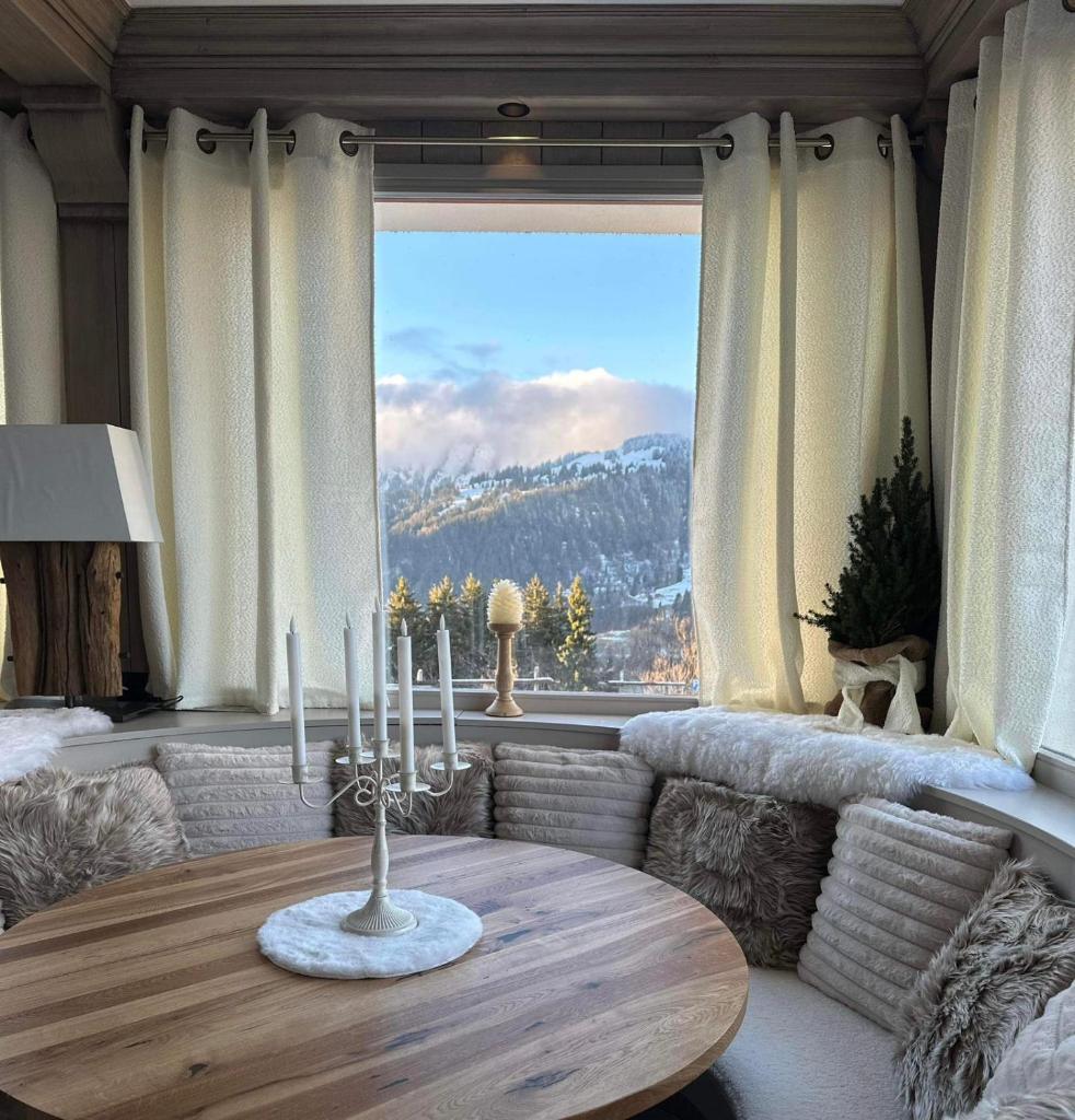 un salon avec une table et une grande fenêtre dans l'établissement Chalet Hotel Le Mont Bisanne, à Crest-Voland