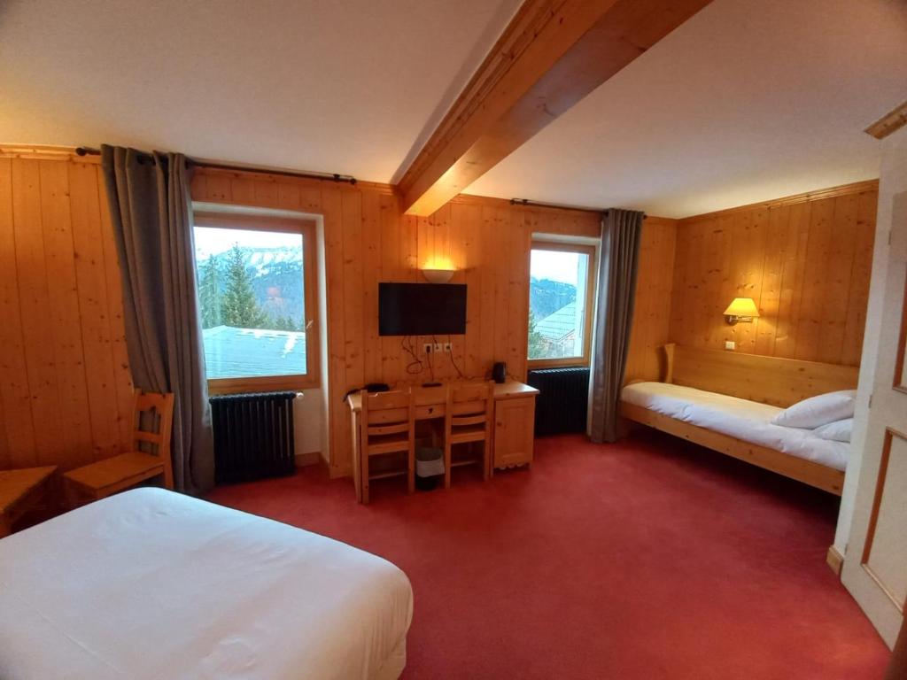 une chambre avec deux lits, un bureau et une télévision dans l'établissement Chalet Hotel Le Mont Bisanne, à Crest-Voland