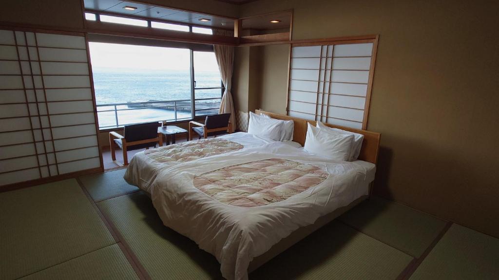 une chambre avec un lit avec vue sur l'océan dans l'établissement Atagawakan, à Higashiizu