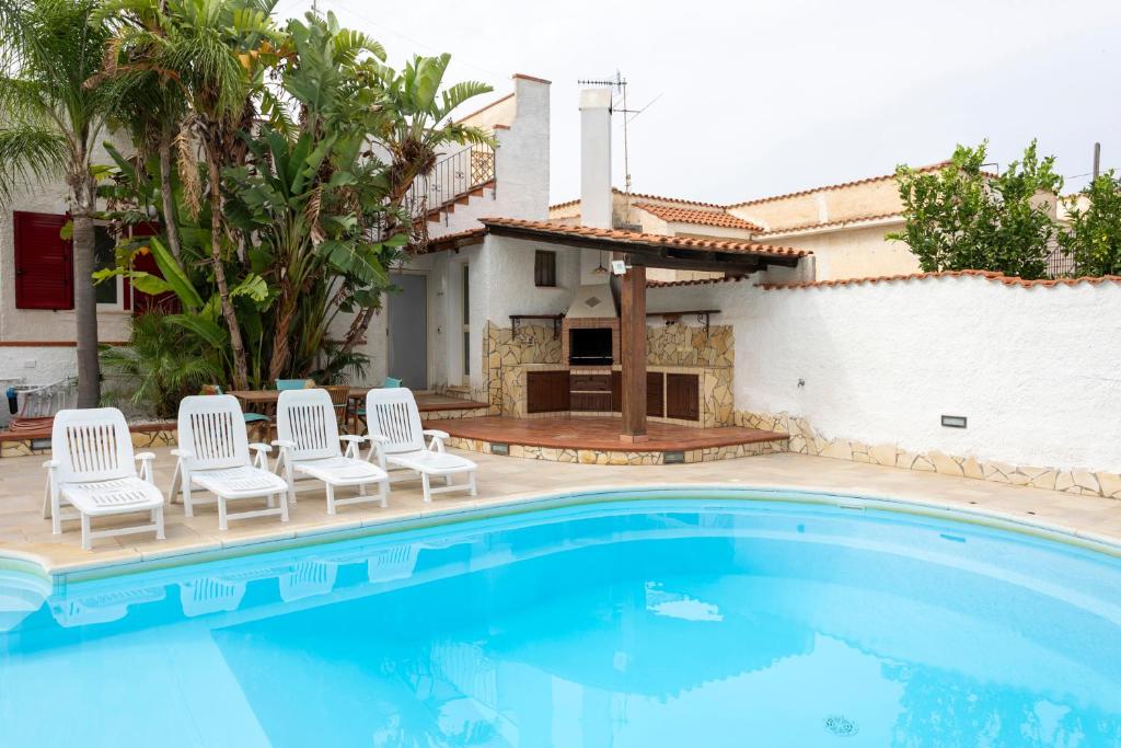 une piscine avec des chaises et une maison dans l'établissement RIFLESSI D'AZZURRO - la vacanza dei tuoi sogni, à Castelvetrano 34 autres photos