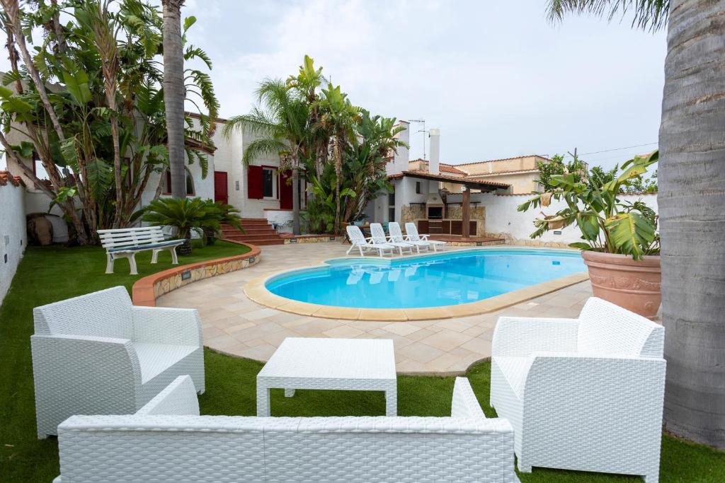 une cour avec une piscine et des chaises blanches dans l'établissement RIFLESSI D'AZZURRO - la vacanza dei tuoi sogni, à Castelvetrano