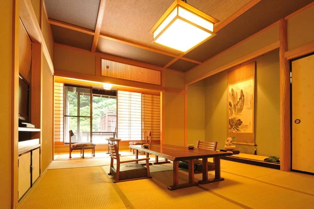 une salle à manger avec une table et une grande fenêtre dans l'établissement Shima Onsen Yoshimoto, à Nakanojo