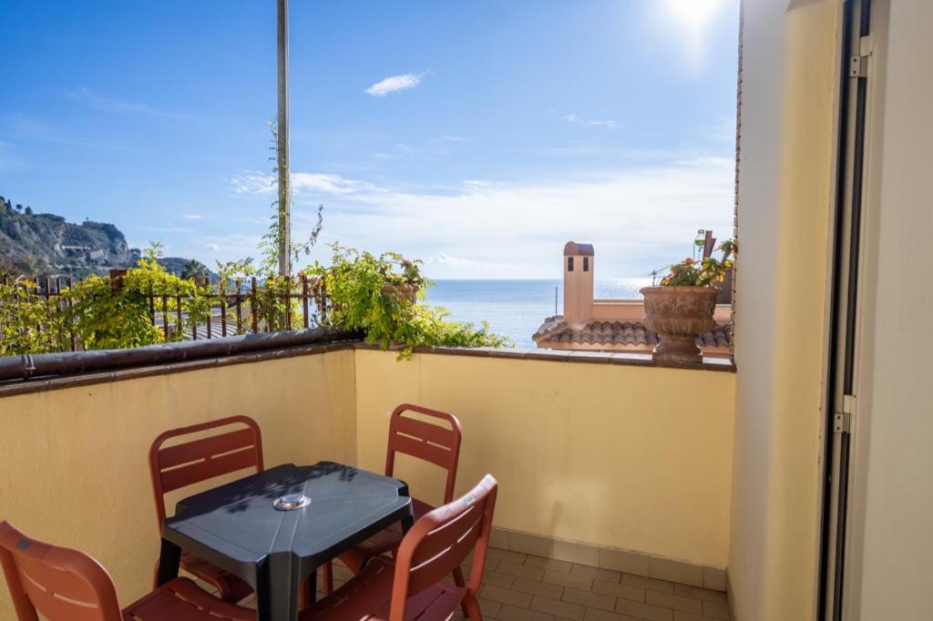une table et des chaises sur un balcon avec vue sur l'océan dans l'établissement Hotel Corallo, à Taormine