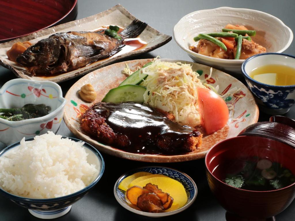 une table avec des plaques alimentaires et des bols de riz dans l'établissement Business Ryokan Iroha, à Minokamo