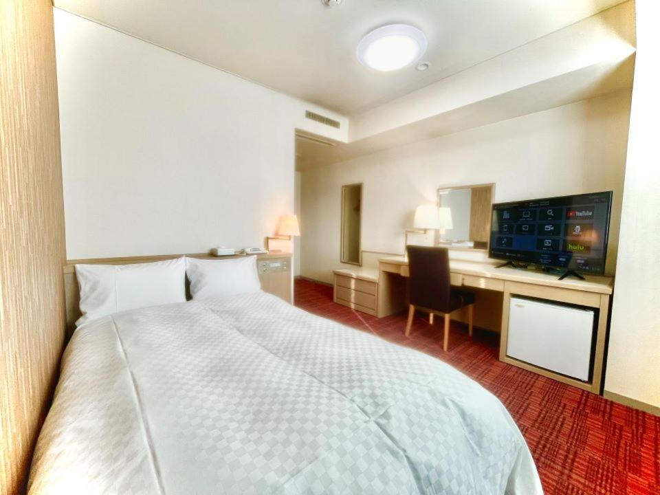 une chambre d'hôtel avec un grand lit et un bureau dans l'établissement Yokote Central Hotel, à Yokote 21 autres photos