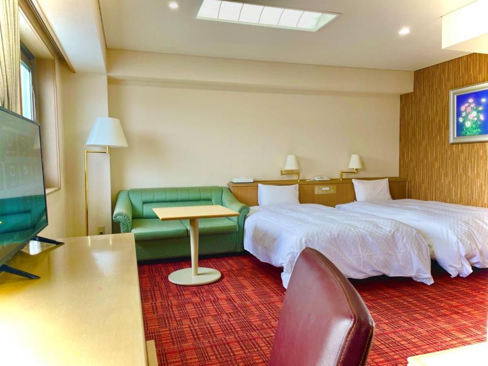 une chambre d'hôtel avec deux lits et un canapé dans l'établissement Yokote Central Hotel, à Yokote
