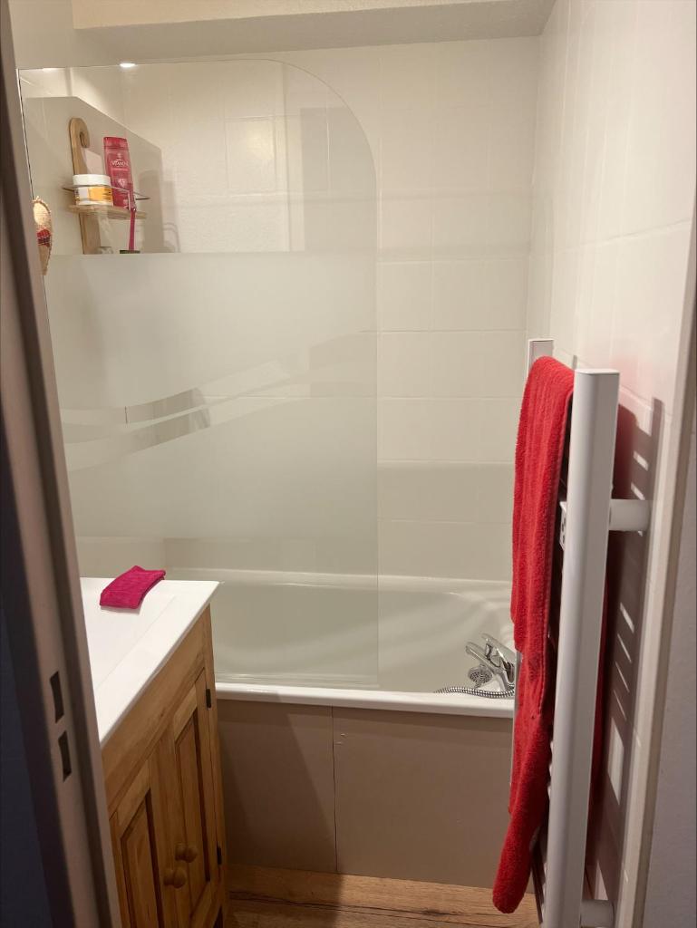 La salle de bains est pourvue d'une baignoire et d'une serviette rouge. dans l'établissement Appart à Puy Saint Vincent 1700 Rés Emeraude, à Puy-Saint-Vincent 12 autres photos