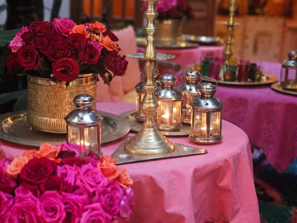 une table avec des lamelles d'argent et des fleurs sur une table rose dans l'établissement Riad Jnane d'Ô, à Marrakech