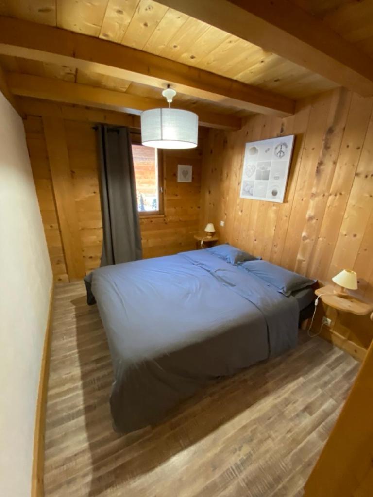 Cette chambre en bois comprend un grand lit. dans l'établissement La Ferme des Georgières "Séjour en tout compris", à Notre-Dame-de-Bellecombe