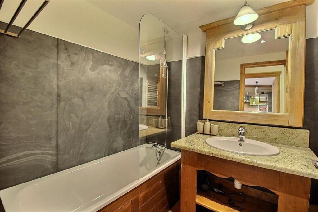 une salle de bain avec un lavabo, une baignoire et un miroir dans l'établissement ARC 1950 - Appartement 5 personnes - ski aux pieds - Sauna, Hammam, Jacuzzi, à Arc 1950 14 autres photos