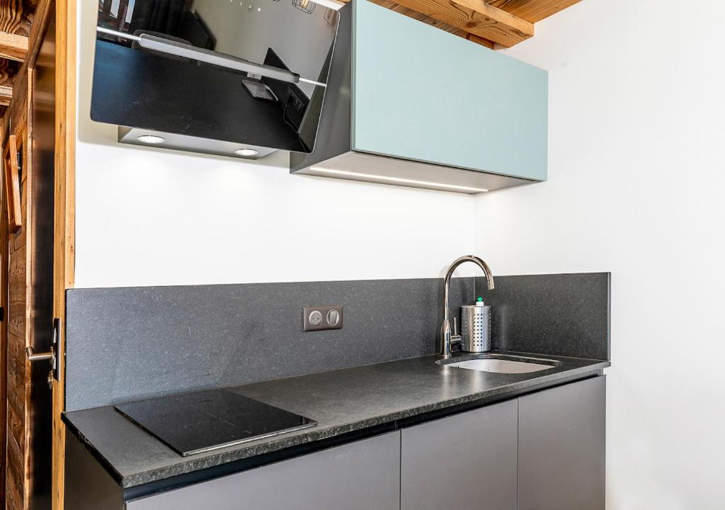 une cuisine avec un évier et un micro-ondes dans l'établissement Val Thorens So Cocooon Silveralp 330, à Val Thorens