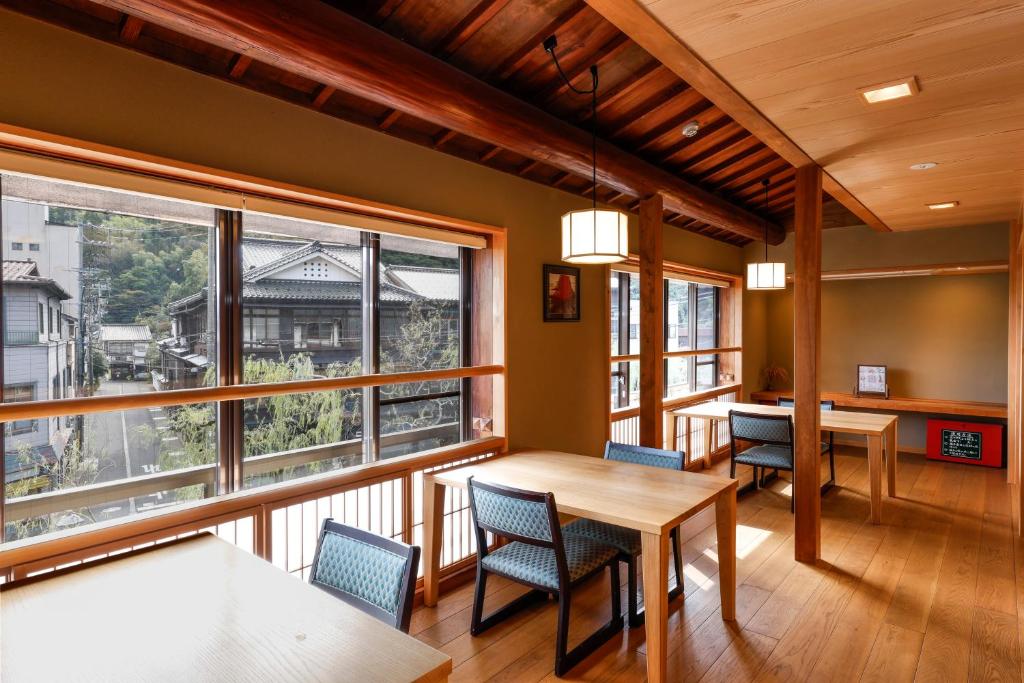 une salle à manger avec une table, des chaises et des fenêtres dans l'établissement Kinosaki Yamamotoya, à Toyooka