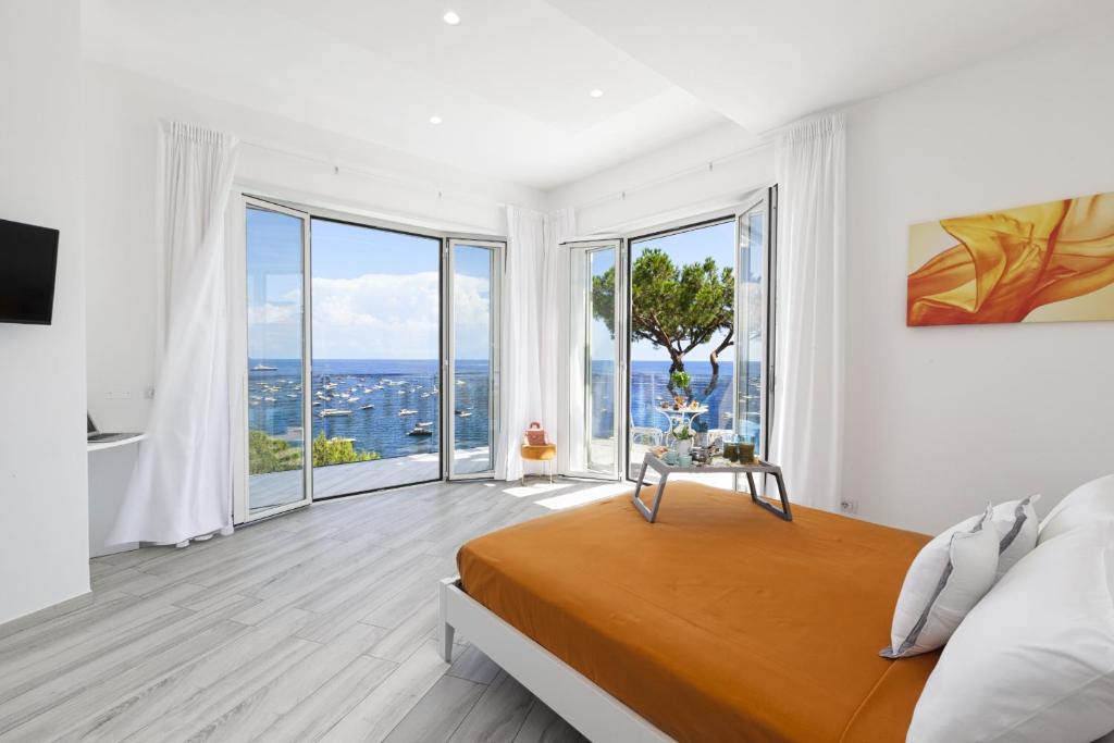 - une chambre blanche avec un lit et de grandes fenêtres dans l'établissement My Exclusive Italy - Villa by the beach with sea-view and Luxury amenities, à Nerano