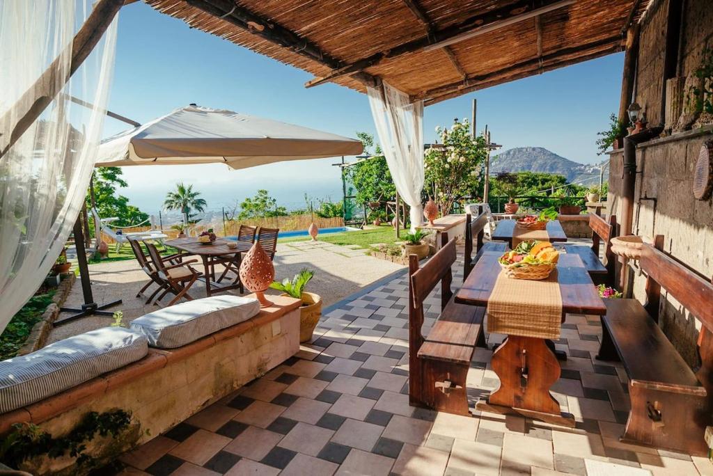 un patio avec une table, des chaises et un parasol dans l'établissement My Exclusive Italy - Villa Sorrento Coast for families - Pool & Views, à Colli di Fontanelle