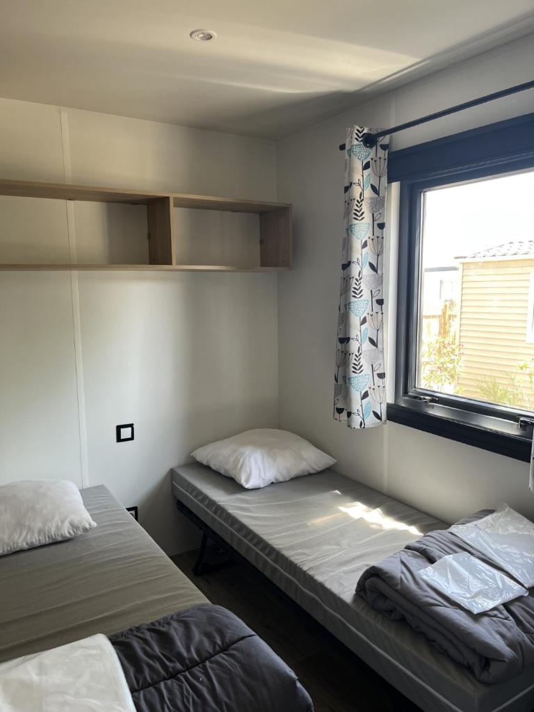 deux lits dans une chambre avec une fenêtre dans l'établissement LES DUNES - Les pieds dans l eau- TORREILLES PLAGE, à Torreilles