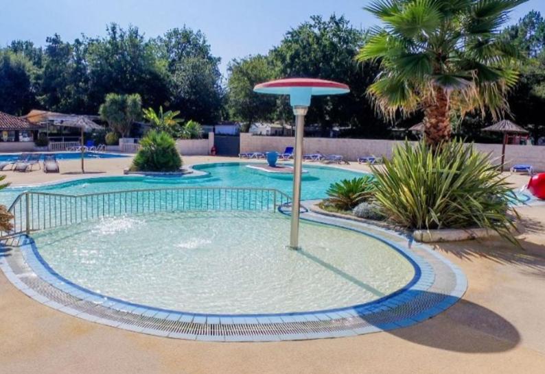 - une piscine avec un parasol dans l'eau dans l'établissement Vacances dans un mobil home climatisé dans les landes entre forêt, lacs et océan,, à Sainte-Eulalie-en-Born