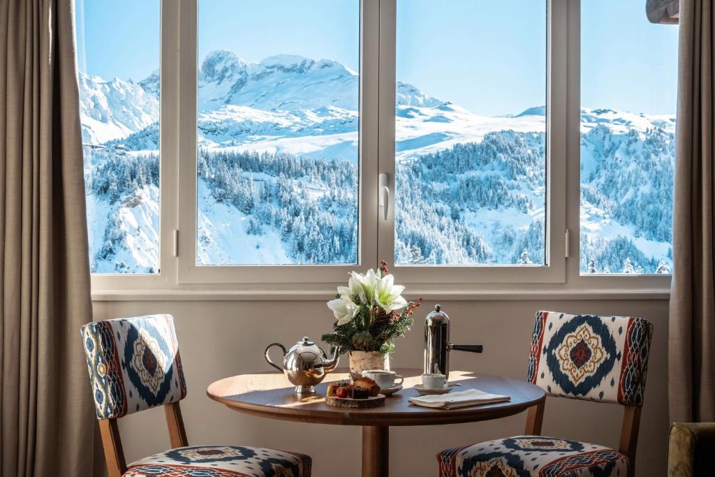 d'une table et de deux chaises avec vue sur les montagnes enneigées. dans l'établissement Alpes Hôtel du Pralong, à Courchevel