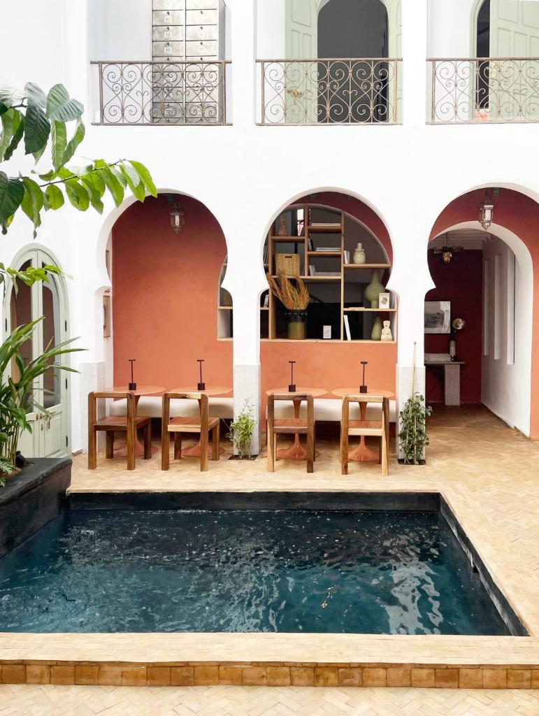 - une piscine d'eau dans une cour avec des tables et des chaises dans l'établissement Riad Al Uzza, à Marrakech
