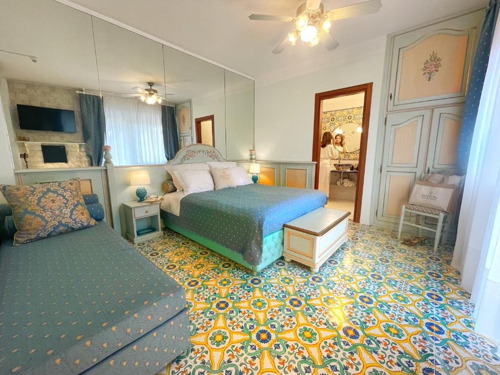 une chambre avec un lit, un canapé et un miroir dans l'établissement Milton Boutique Hotel - Adults Only, à Lido di Jesolo