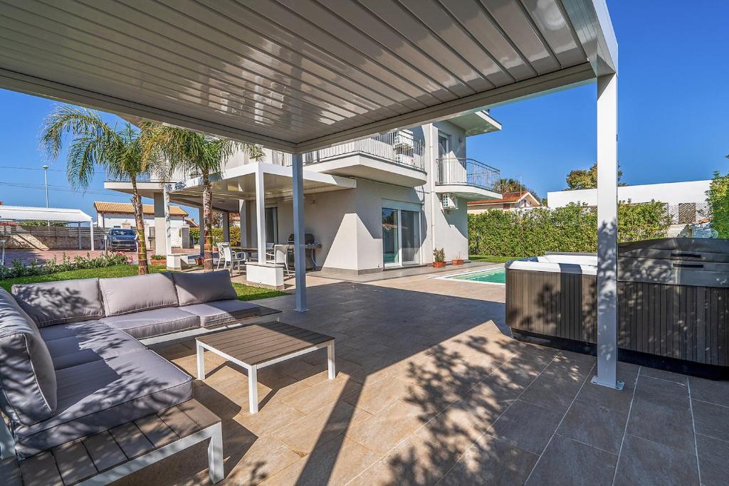 une terrasse avec un canapé, une table et un grill dans l'établissement Villa Nigró, à Syracuse