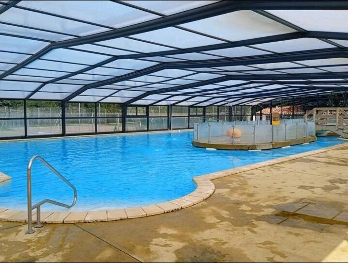 une grande piscine avec de l'eau bleue dans un immeuble dans l'établissement Le Kraken, à Aureilhan