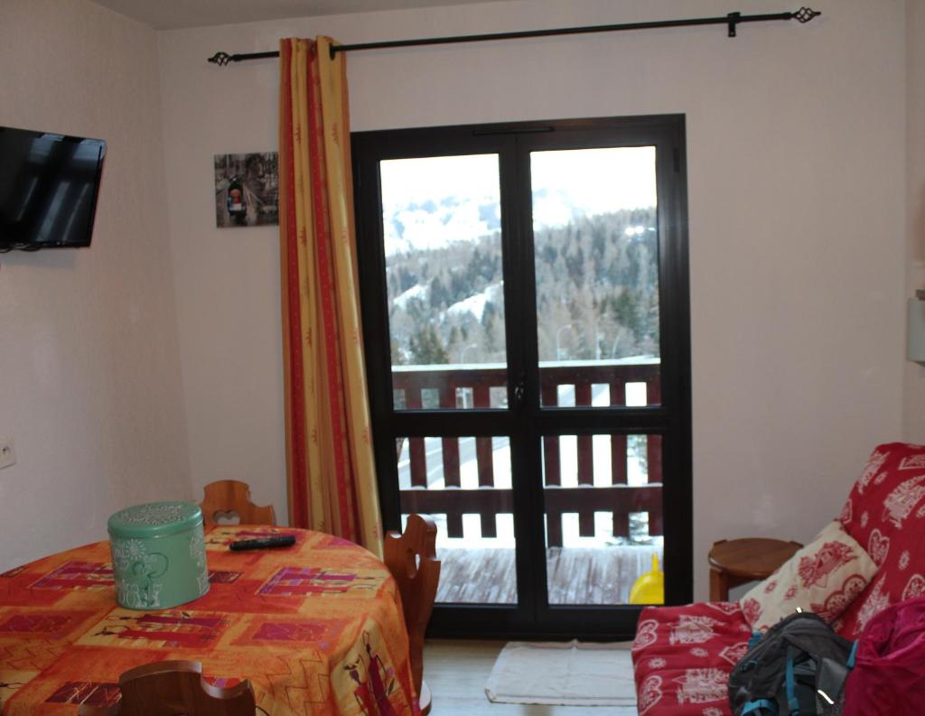 Cette chambre dispose d'une table et d'une porte en verre avec vue. dans l'établissement Appartement Superdévoluy les 4 Géants, à Superdevoluy