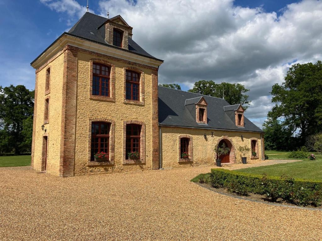 un bâtiment en briques avec une tour en haut dans l'établissement Luxueux gîte avec piscine et Wifi, proche circuit 24H du Mans, animaux bienvenus - FR-1-410-430, à Les Bouleaux