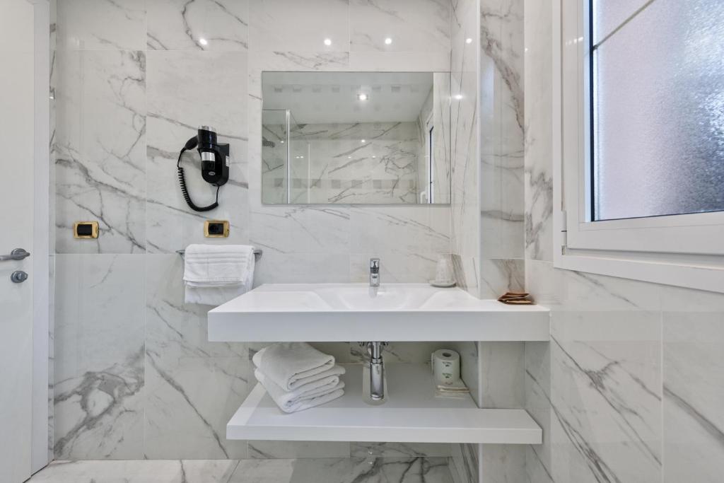 une salle de bain blanche avec un lavabo et un miroir dans l'établissement Columbus Dependance, à Lignano Sabbiadoro 26 autres photos