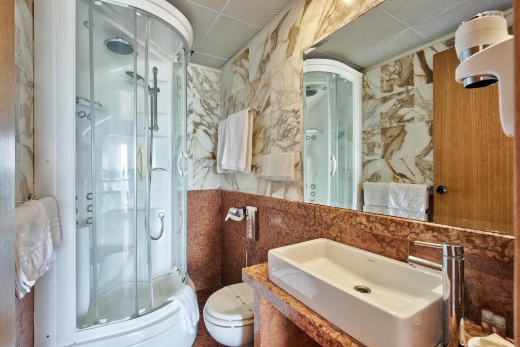 une salle de bain avec un lavabo et une douche dans l'établissement Hotel Columbus, à Lignano Sabbiadoro