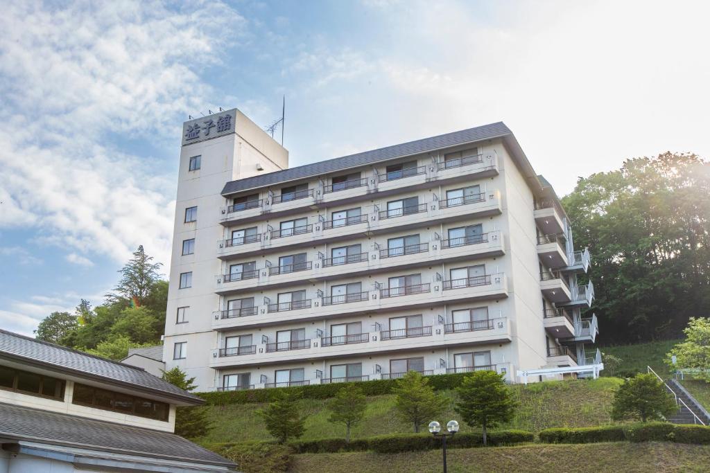 un bâtiment blanc au sommet d'une colline dans l'établissement Mashikokan Satoyama Resort Hotel, à Mashiko