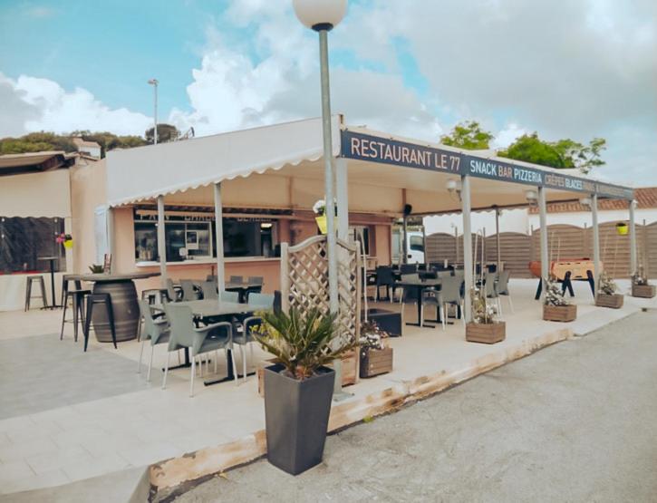 un restaurant avec des tables et des chaises devant un bâtiment dans l'établissement Camping Europcamping, à Fréjus