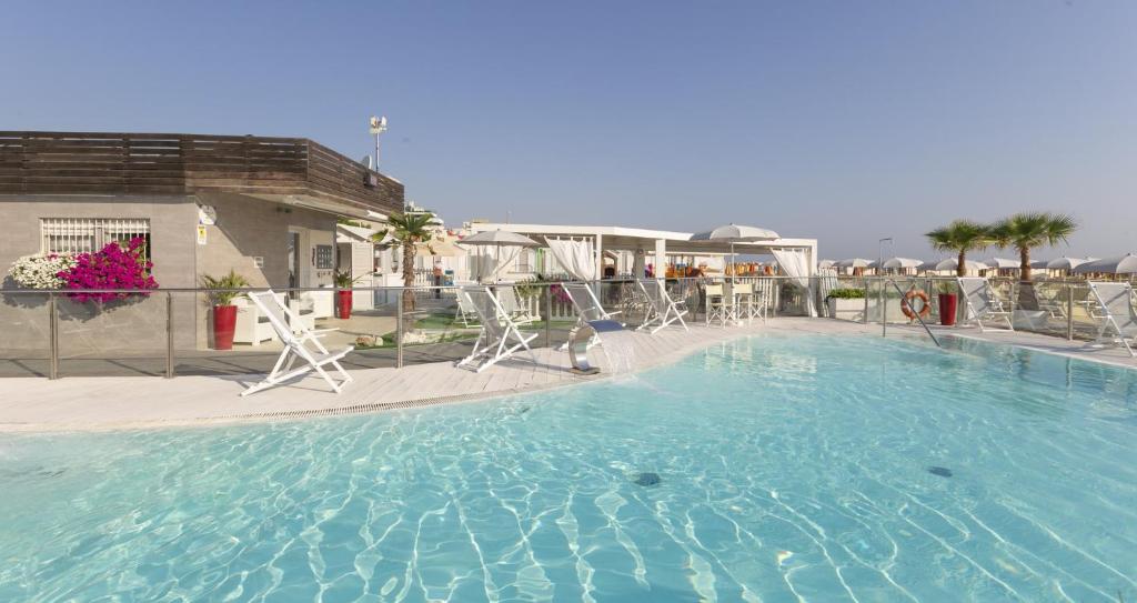 - une grande piscine avec un enfant dans l'eau dans l'établissement Hotel Pacific, à Riccione