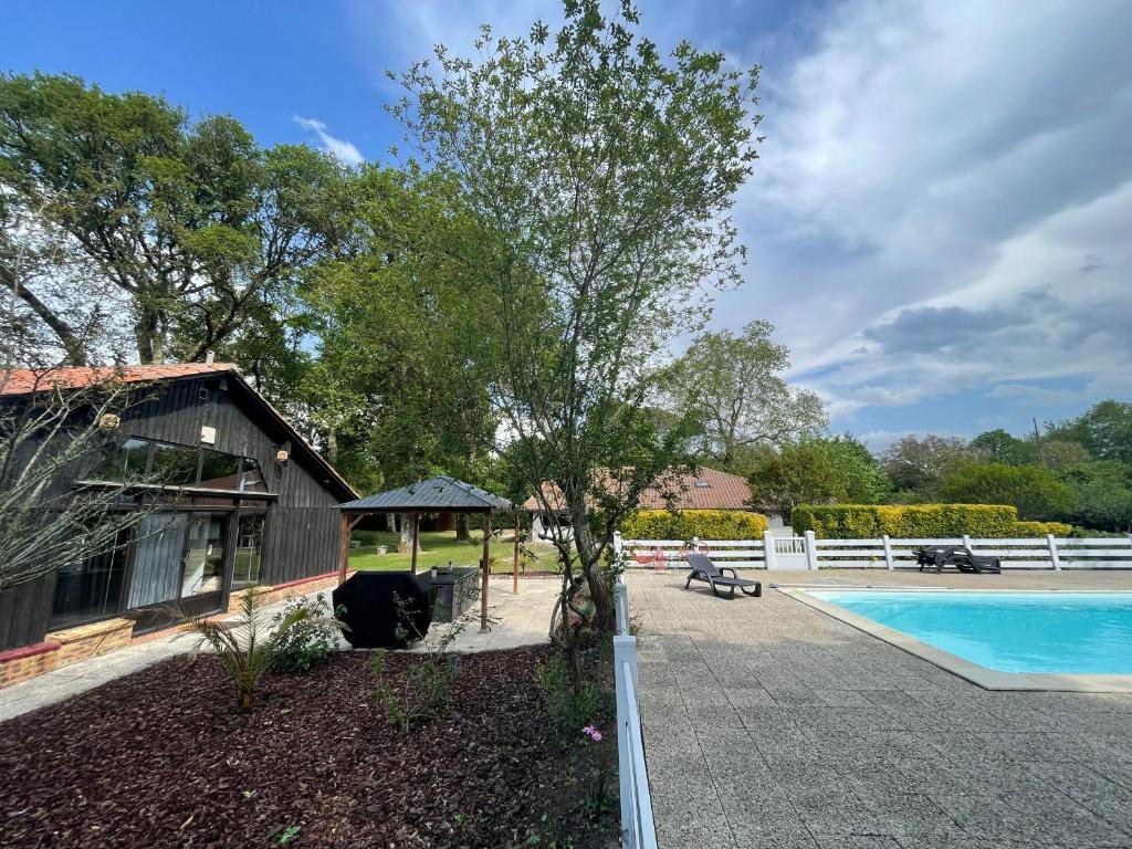 une maison avec une piscine à côté d'une clôture blanche dans l'établissement L Uni Vert d Azur gite 10 pers piscine et mini ferme proche océan, à Azur