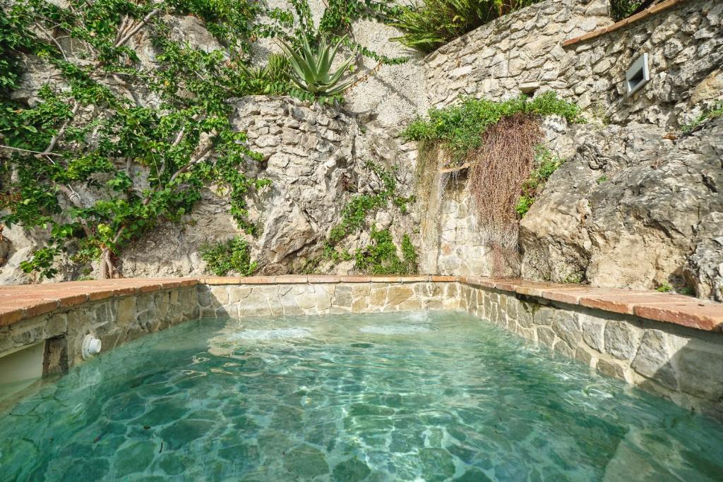 une mare d'eau devant un mur de pierre dans l'établissement Hotel Botanico San Lazzaro, à Maiori