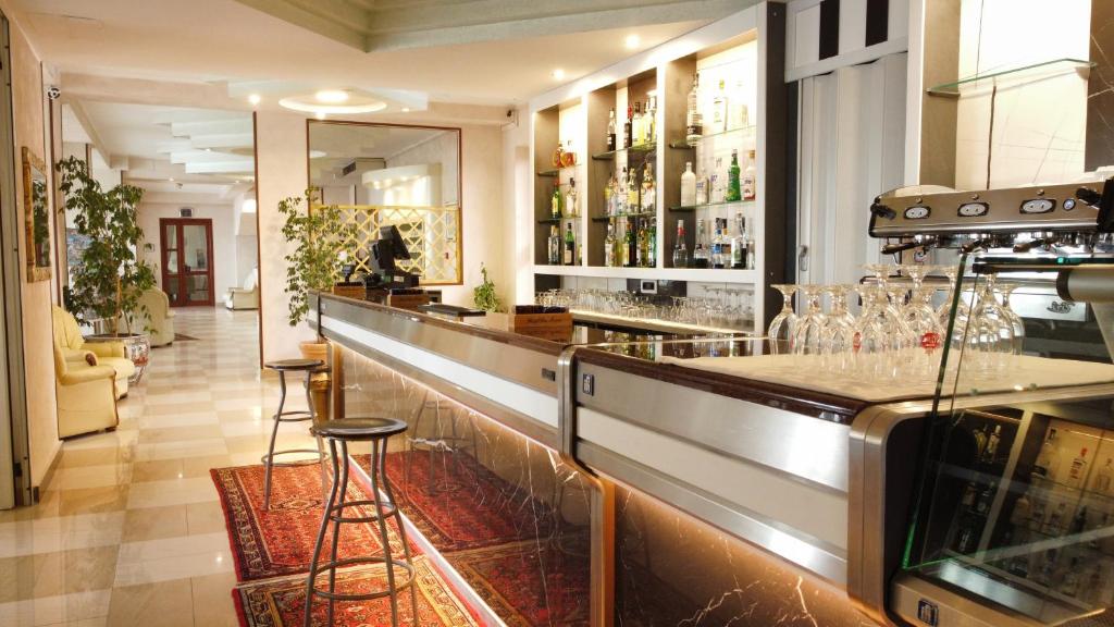 - un bar avec un comptoir et des tabourets dans une pièce dans l'établissement Hotel San Marco, à Alghero
