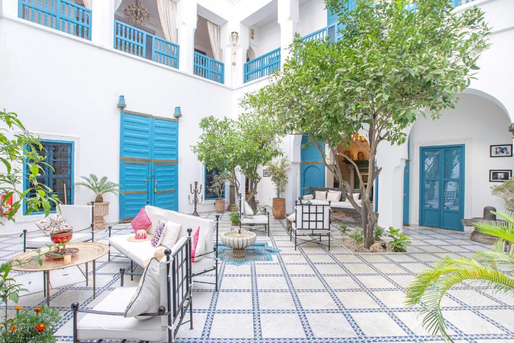 une terrasse avec des portes, des chaises et des arbres bleus dans l'établissement Riad Khalifa, à Marrakech