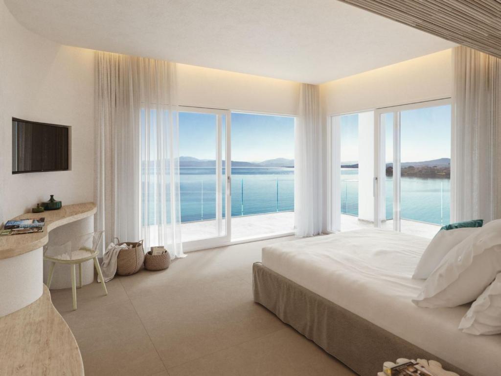 une chambre avec un grand lit et de grandes fenêtres dans l'établissement Gabbiano Azzurro Hotel & Suites, à Golfo Aranci