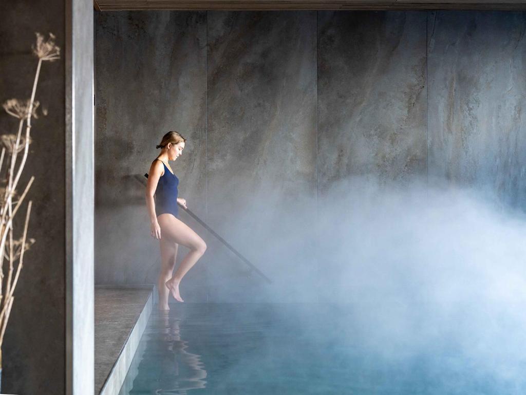 une femme debout dans un bassin d'eau bleue dans l'établissement Hôtel Le Diamond Rock, à Tignes