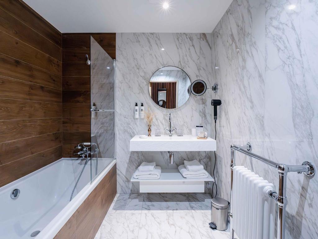 une salle de bain avec un lavabo, une baignoire et un miroir dans l'établissement Hôtel Le Diamond Rock, à Tignes
